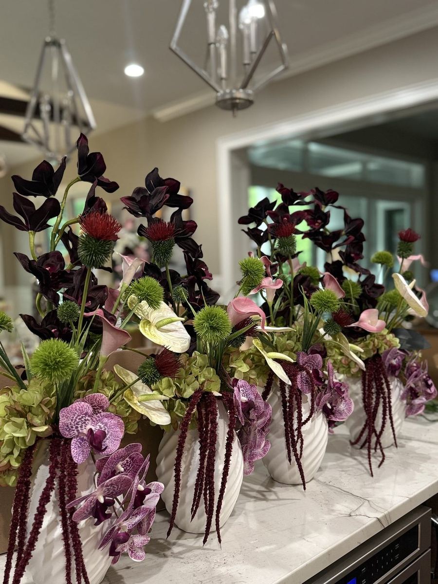 Plum and orchid floral arrangements in white vessels