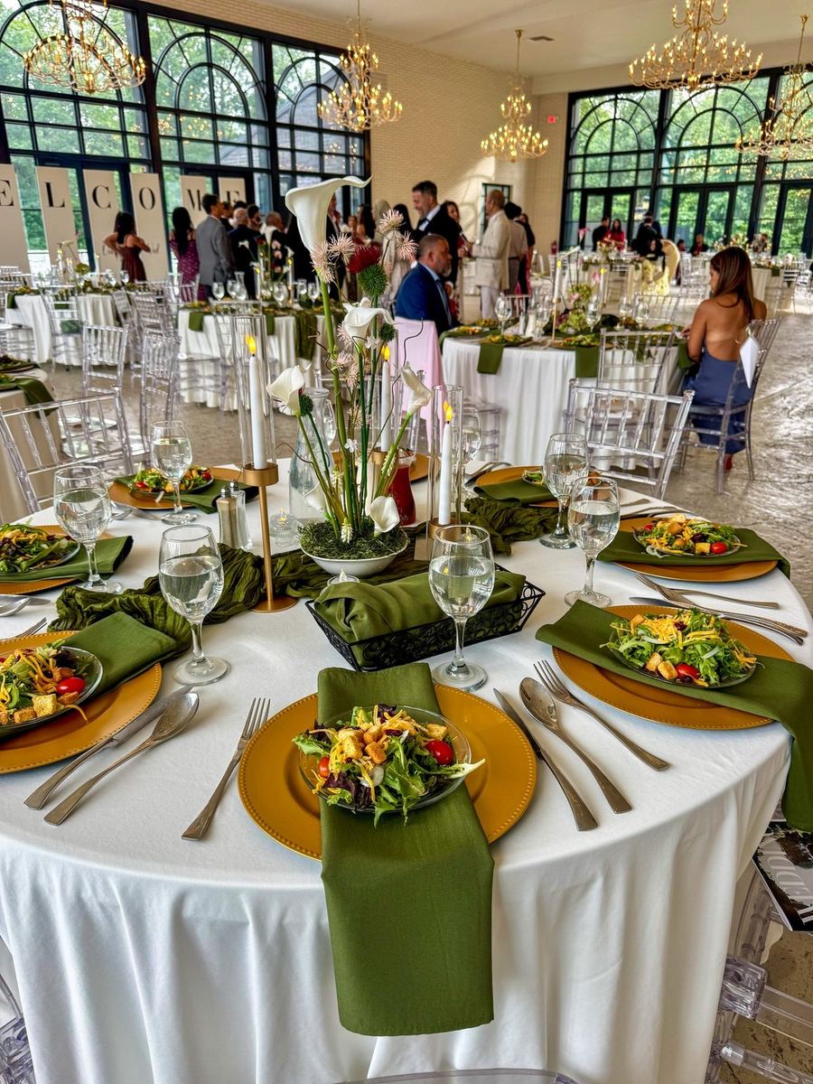 Styled wedding reception tables with gold chargers and green velvet napkins