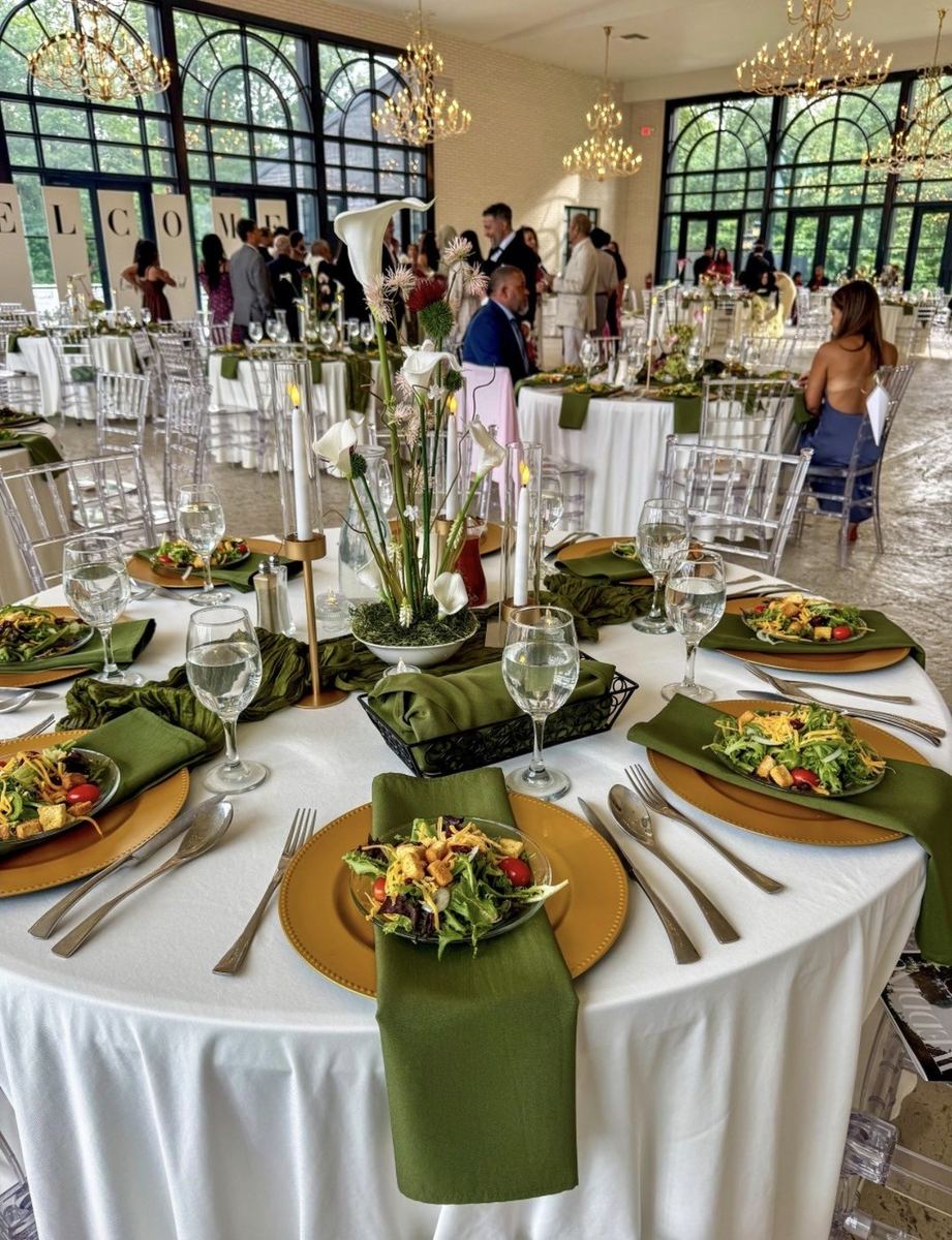 Wedding reception tablescape with gold chargers and green napkins
