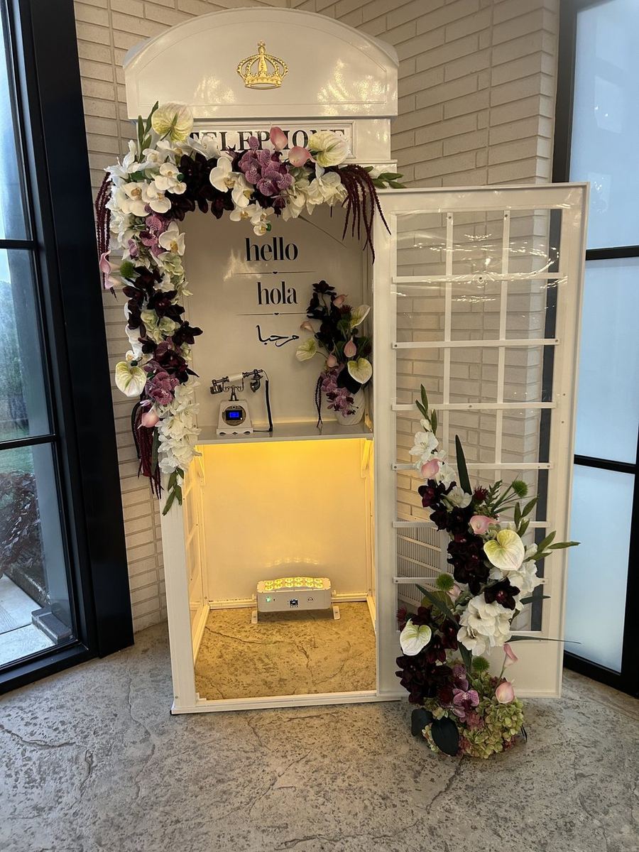 Illuminated telephone booth audio guestbook with floral installation